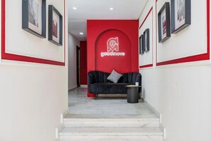 A hallway with a red wall, a black sofa, and framed pictures on the walls. - The Loft  (Casablanca)