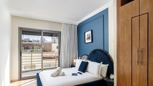 Ein Schlafzimmer mit Bett, Kleiderschrank, Fenster mit Blick und einem gerahmten Bild an der Wand.