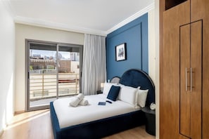 Un dormitorio con cama, armario, ventana con vistas y un cuadro en la pared.