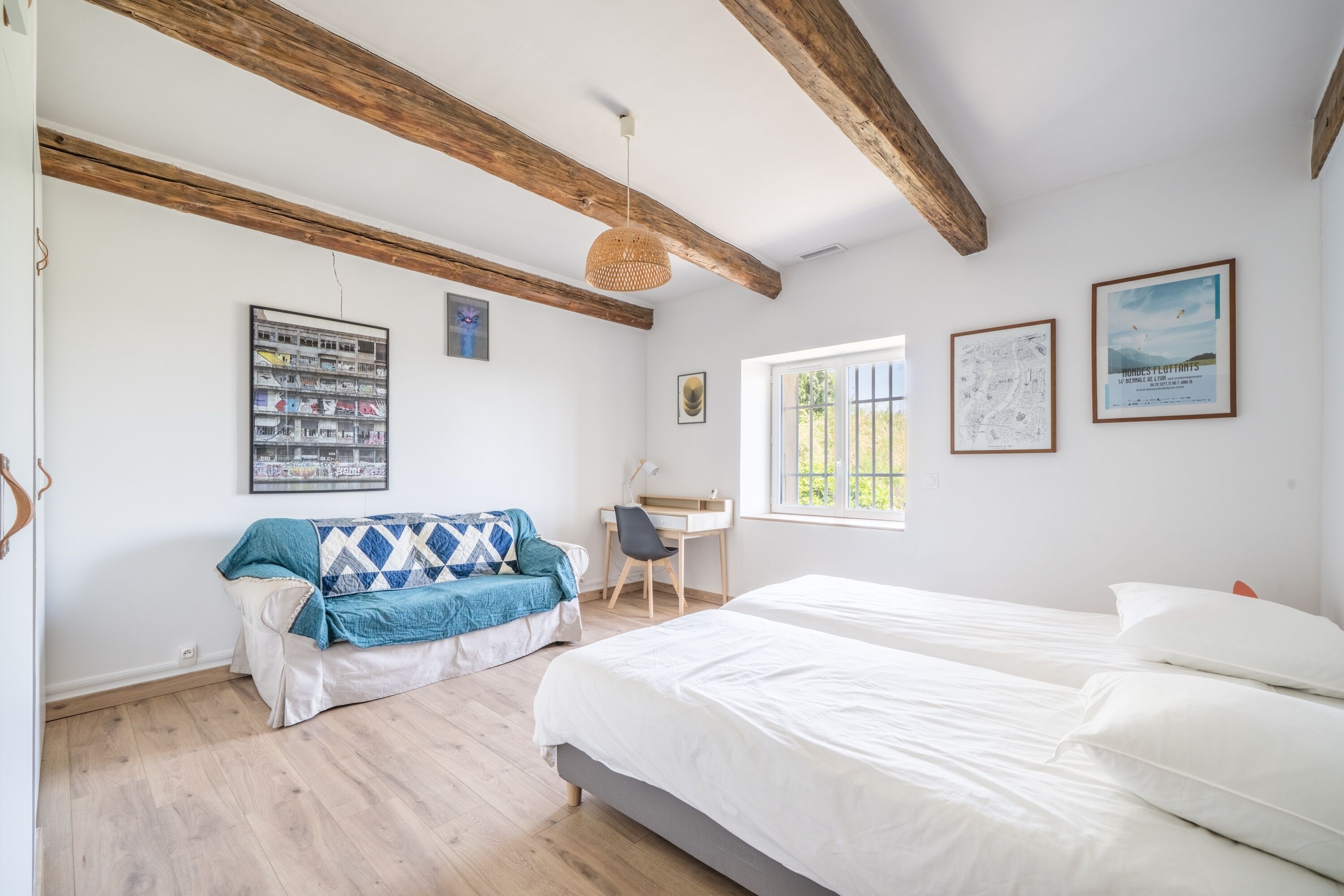 Un dormitorio con techo de madera, una cama, un escritorio, una silla y una ventana.