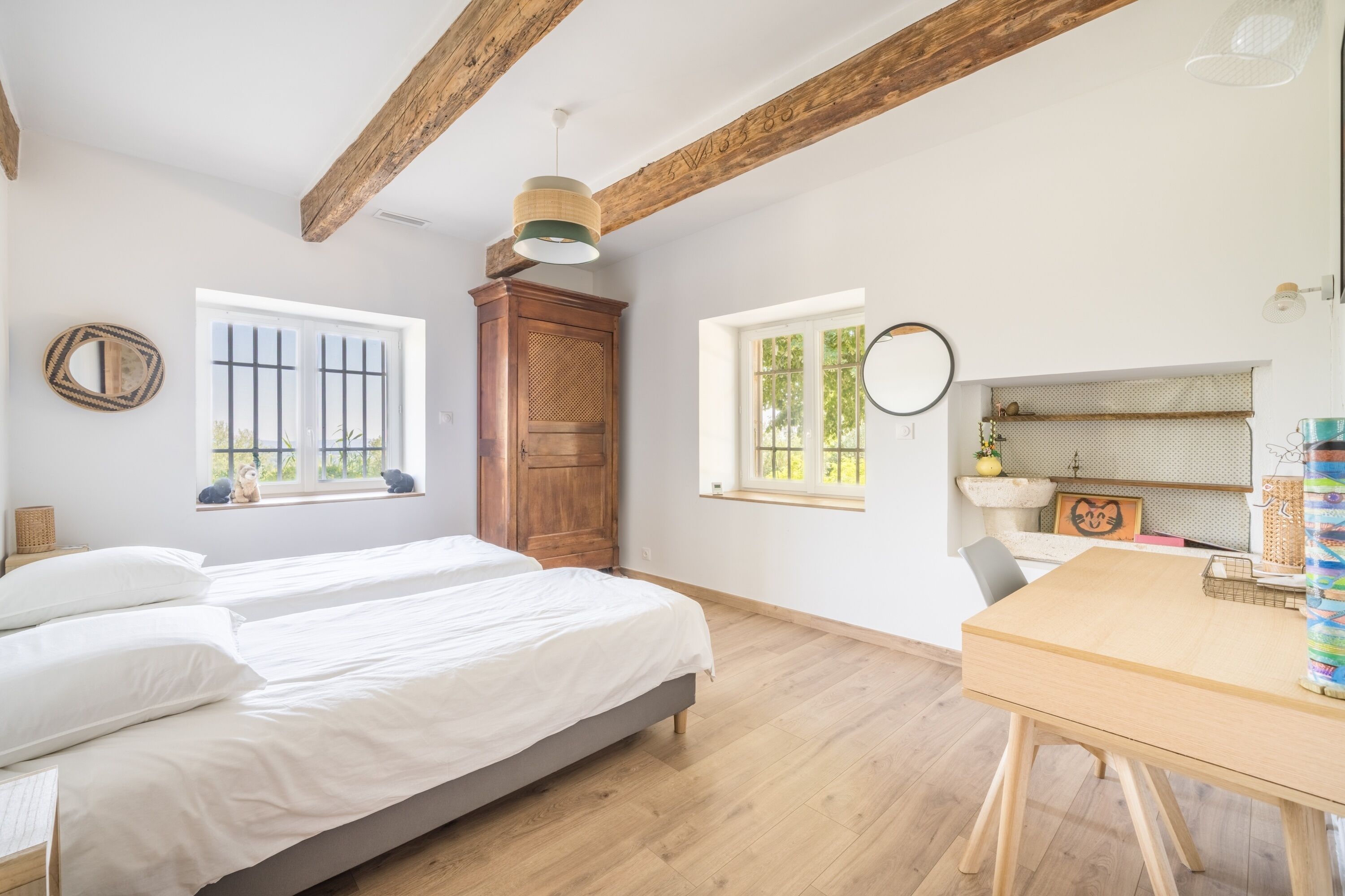 A room with a bed, a wooden table, and a window with a view.