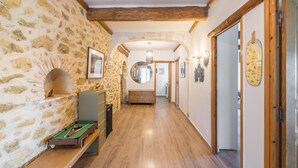 Un pasillo con paredes de piedra, vigas de madera, una mesa de billar y un espejo.