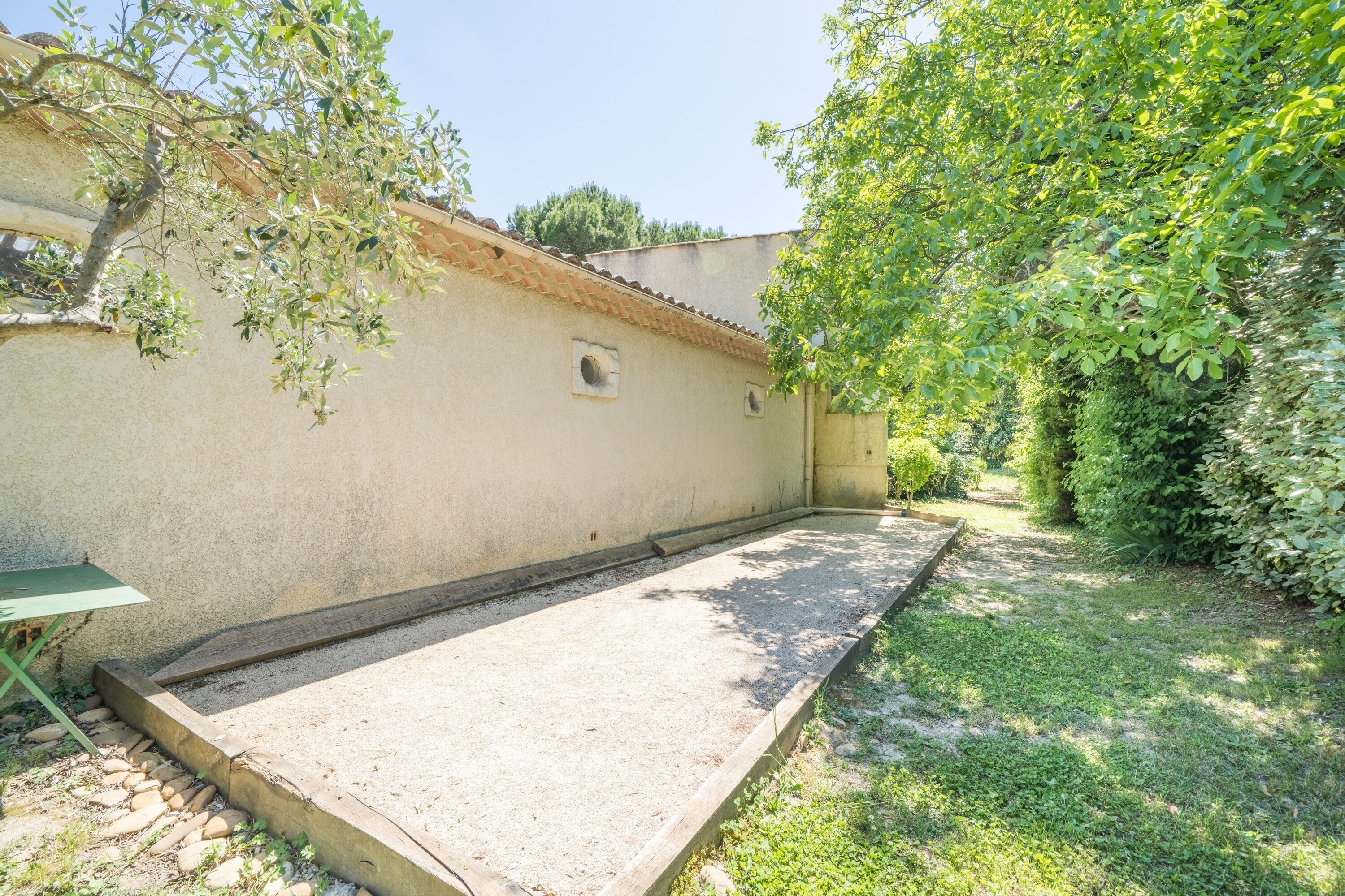 A courtyard with a concrete play area, a small table, and a wall with a window.