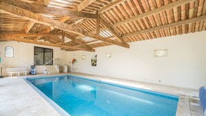 Una piscina interior con techo de madera y paredes de azulejos.