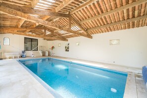 Una piscina interior amb sostre de fusta i parets de rajola.