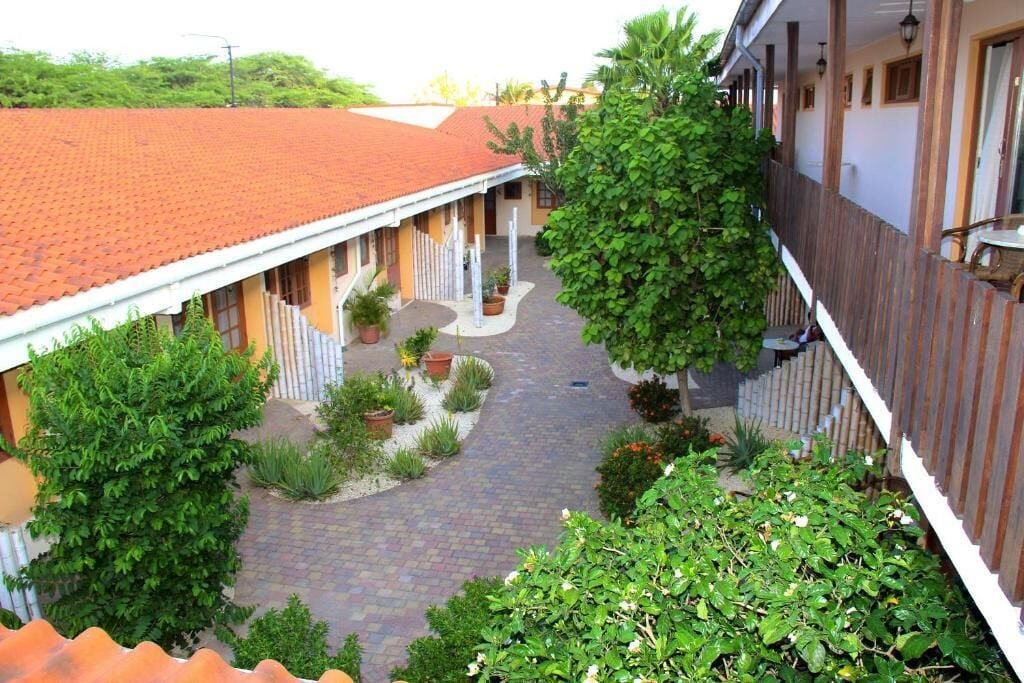 A courtyard with a tiled roof, potted plants, and a wooden fence.
