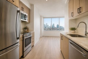 Eine moderne Küche mit Edelstahlgeräten, Holzschränken, einem großen Fenster mit Blick auf die Stadt und einem Spülbecken mit modernem Wasserhahn.