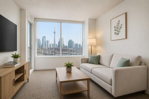 Ein modernes Wohnzimmer mit Blick auf die Stadt, einem Flachbildfernseher, einem Sofa, einem Couchtisch und einer Lampe.