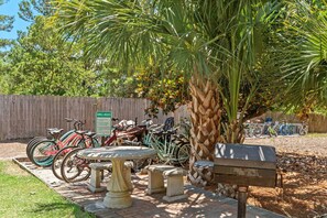 Een terras met een tafel en banken, een houten hek en fietsen die ertegenaan staan.