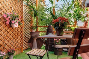 A wooden table with chairs, surrounded by potted plants and a wooden fence. - Roma Termini Sapienza Rooms (Rome)