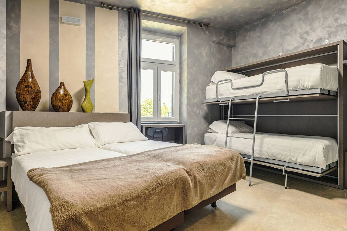 A bedroom with a large bed, a bunk bed, and three vases on a shelf.