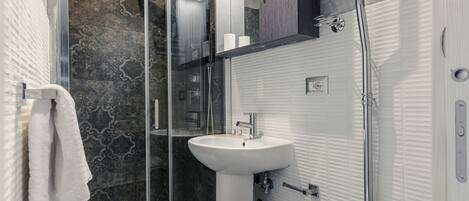 A modern bathroom with a glass shower enclosure, a white sink, and a toilet.