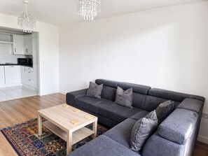 Ein modernes Wohnzimmer mit einem grauen Ecksofa, einem Holztisch und einem gemusterten Teppich.