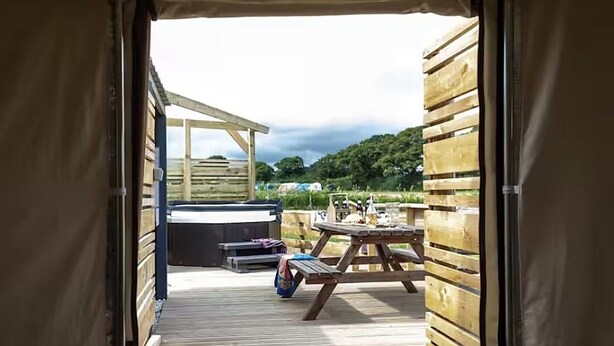 A wooden deck with a picnic table and a hot tub. - Yurt with Private Hot Tub and Bathroom (Bridport)