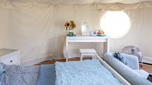 A tented room with a bed, a desk with a laptop, a fan, and a window. - Yurt with Private Hot Tub and Bathroom (Bridport)