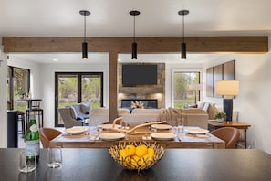 A dining area with a wooden table, chairs, a bowl of fruit, and a fireplace. - Outpost: Teton Shadows Wister H - Teton Views! (Jackson)