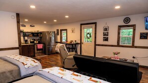 Una habitación acogedora con dos camas, un kitchenette, una zona de comedor y vistas al exterior.