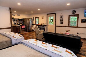 A cozy room with two beds, a kitchenette, a dining area, and a view of the outdoors. - Sweet Serenity Cabin Dunlap Tennessee (Dunlap)