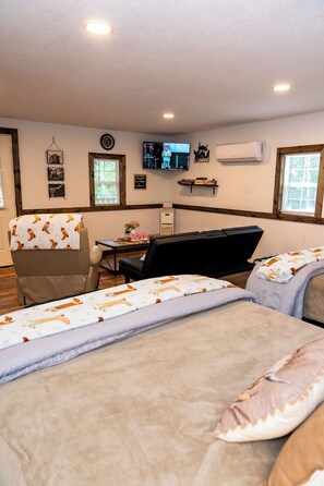 Ein Zimmer mit zwei Betten, einem Schreibtisch, einem Stuhl, einem Fernseher und einer Klimaanlage.