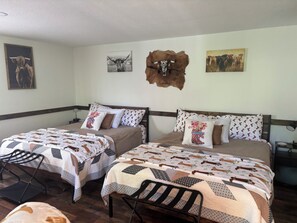A room with two beds, a wooden headboard, a wall-mounted animal hide, and a painting of cows. - Sweet Serenity Cabin Dunlap Tennessee (Dunlap)