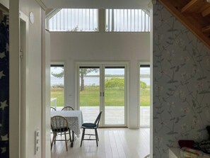 Une pièce avec une table et des chaises, donnant sur l’extérieur, et une porte menant à l’extérieur.