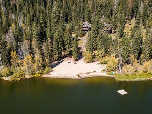 Eine Lodge, umgeben von dichtem Wald, einem Sandstrand und einem kleinen Steg.