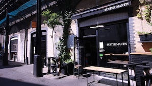 Ein Restaurant namens 'Buster Mantis' mit Außenbereich und einer Ziegel-Fassade.
