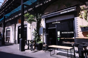 Ein Restaurant namens 'Buster Mantis' mit Außenbereich und einer Ziegel-Fassade.