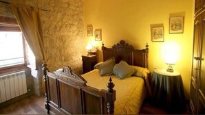 A bedroom with a stone wall, wooden bed frame, and two bedside lamps. - La Casa de las Monjas (Miranda de Arga)