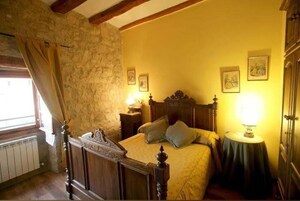 Un dormitorio con pared de piedra, estructura de cama de madera y dos lámparas de noche.