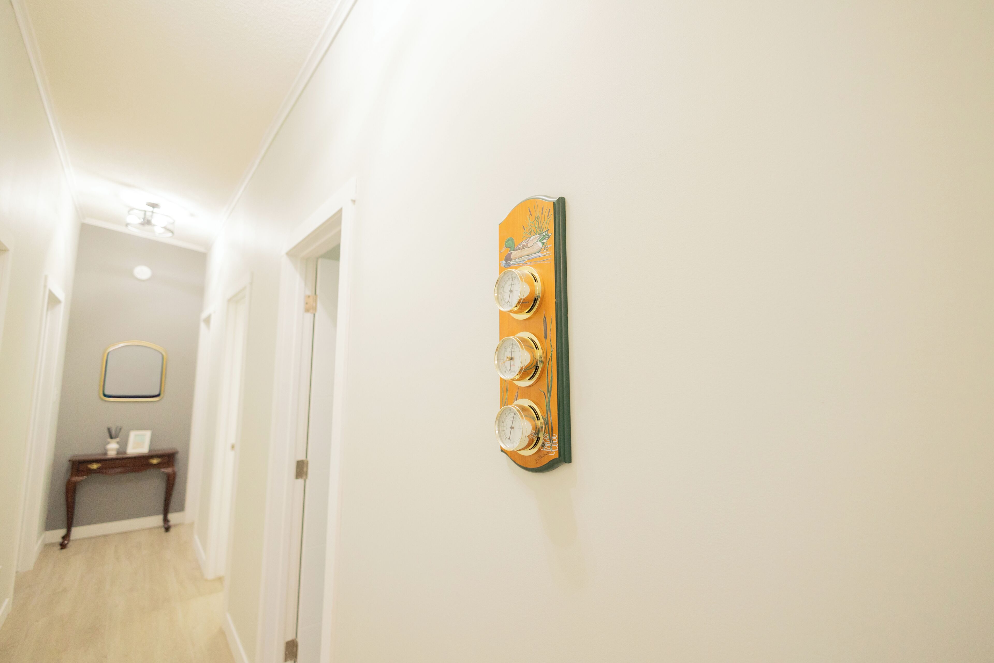 A hallway with a wall-mounted clock, a mirror, and a small console table.