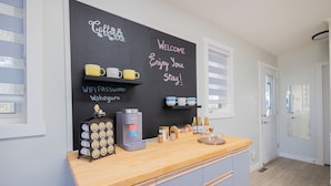 A modern kitchen with a coffee station, a chalkboard with messages, and a wooden countertop. - Lakeview Escape at Gimli by Guest Expertise (gimli)