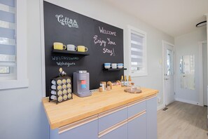 A modern kitchen with a coffee station, a chalkboard with messages, and a wooden countertop.