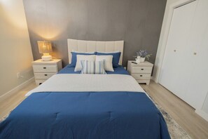 A bedroom with a bed, nightstands, a lamp, and a wardrobe.