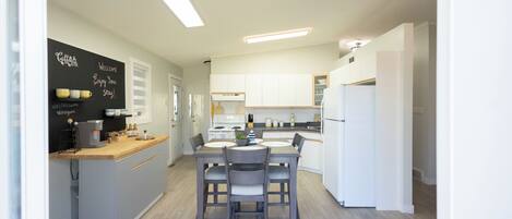 A modern kitchen with a central island, white cabinetry, and a chalkboard with writing.