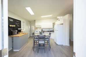 A modern kitchen with a central island, white cabinetry, and a chalkboard with writing.