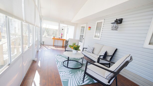 A spacious room with a wooden floor, a white sofa, a round coffee table, and a view through large windows. - Lakeview Escape at Gimli by Guest Expertise (gimli)