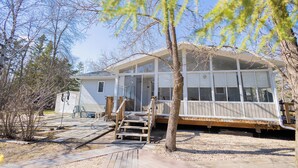 A house with a covered porch, a wooden staircase, and a gravel driveway. - Lakeview Escape at Gimli by Guest Expertise (gimli)