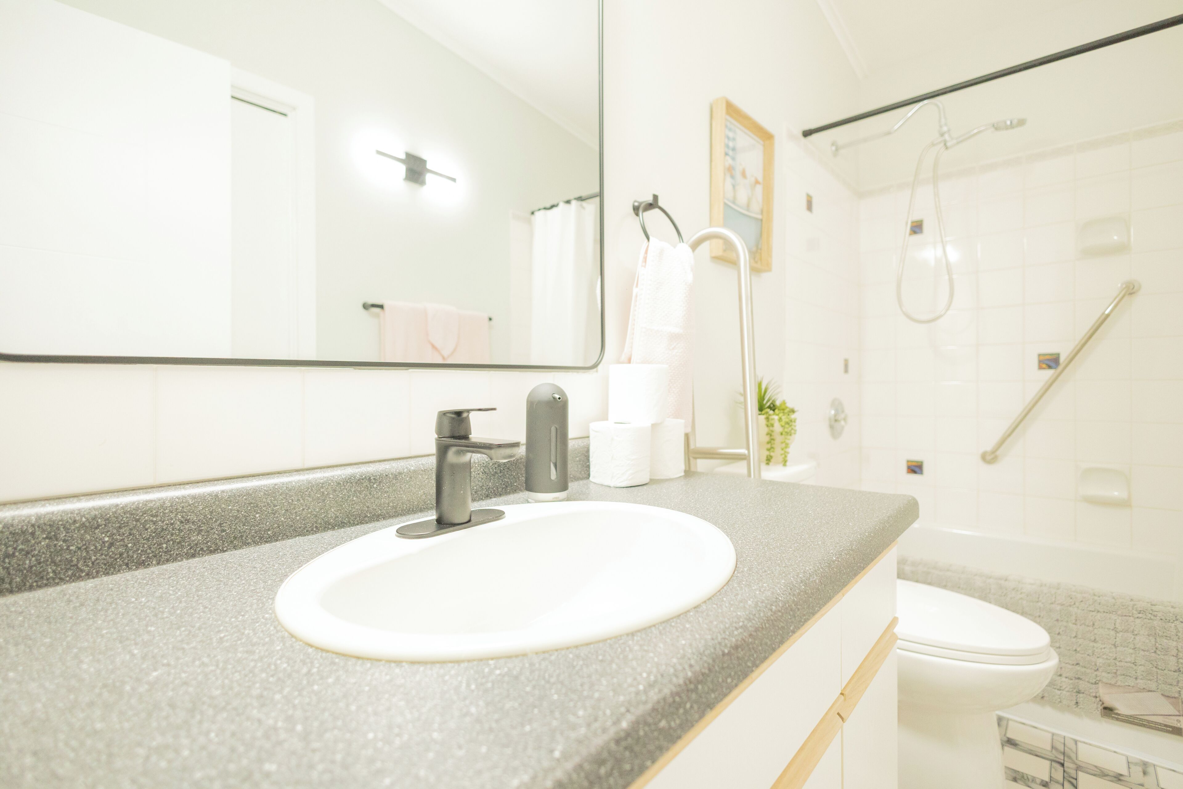 Un baño con lavamanos blanco, espejo, ducha e inodoro.