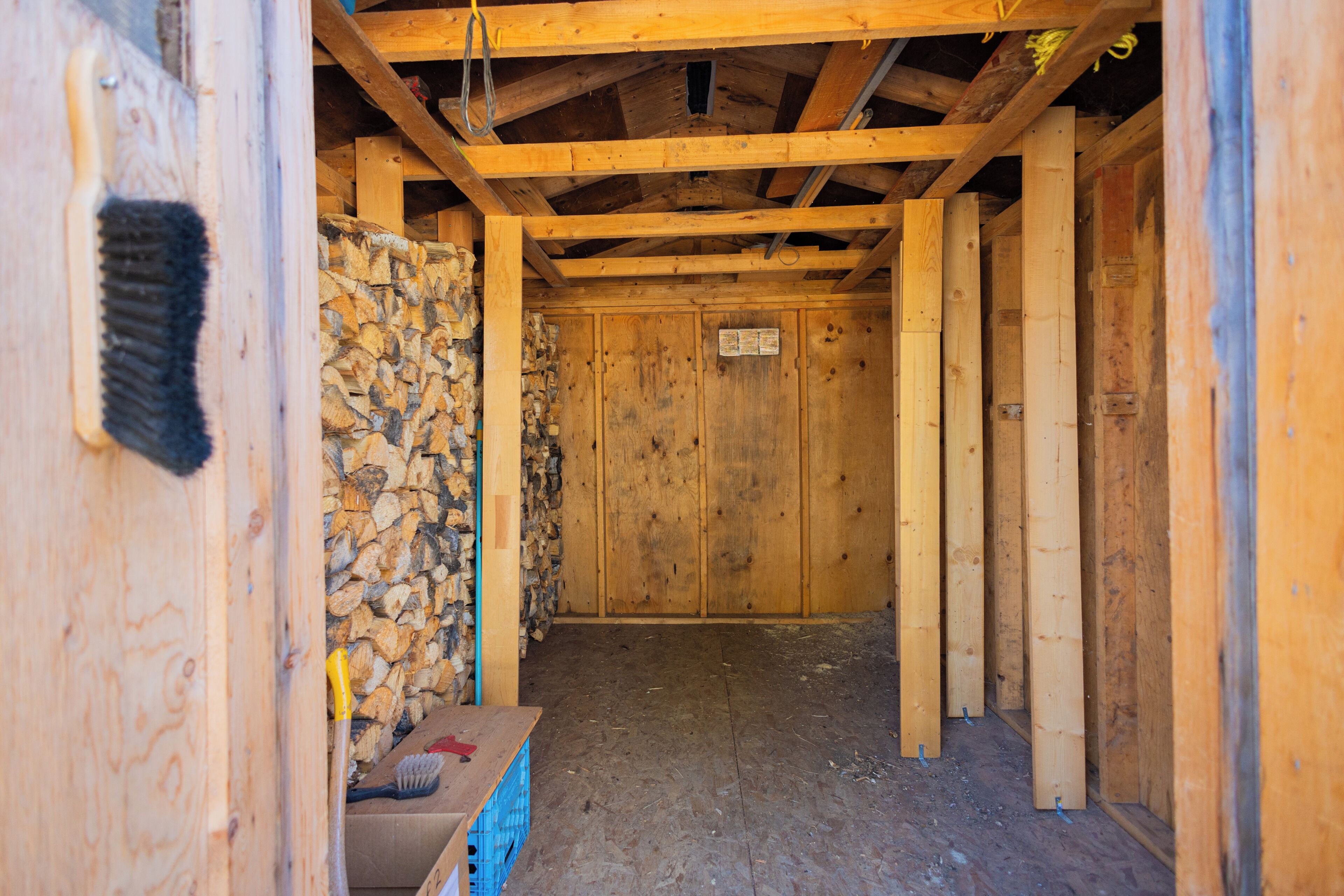 Un intérieur en bois avec des poutres apparentes, un mur en pierre et une caisse bleue.