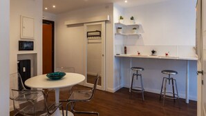 Een moderne keuken met een wit aanrecht, barstoelen en een ronde eettafel met stoelen.