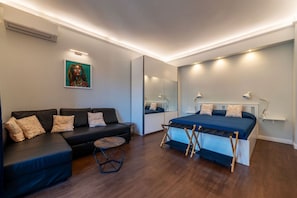 Ein modernes Schlafzimmer mit einem Bett, einem Sofa, einem kleinen runden Tisch und einem Spiegel.