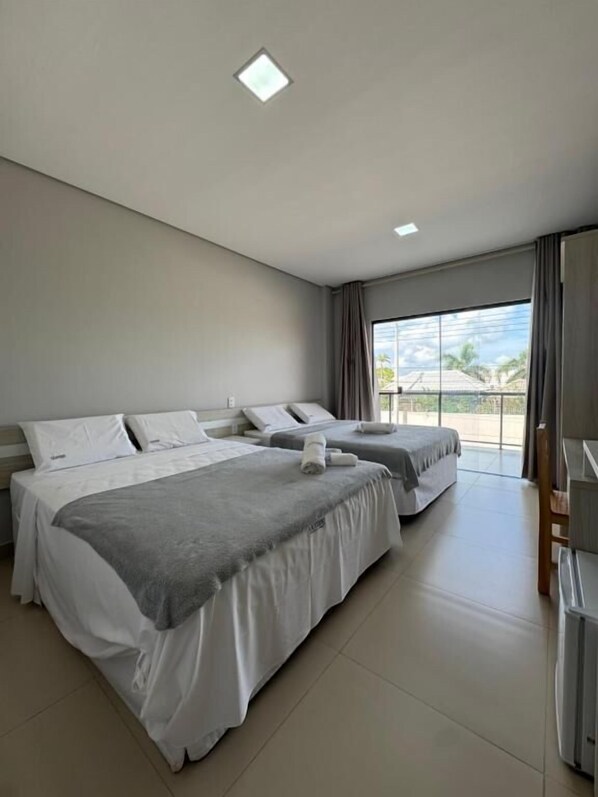 A hotel room with two beds, a desk, and a large window with a view.