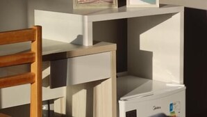 A bedroom with a bed, a wooden chair, a TV, and two framed pictures on a shelf. - Oceane Norte Hotel (Parnaíba)