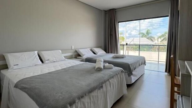A hotel room with two beds, a large window, and a view of the outdoors. - Oceane Norte Hotel (Parnaíba)
