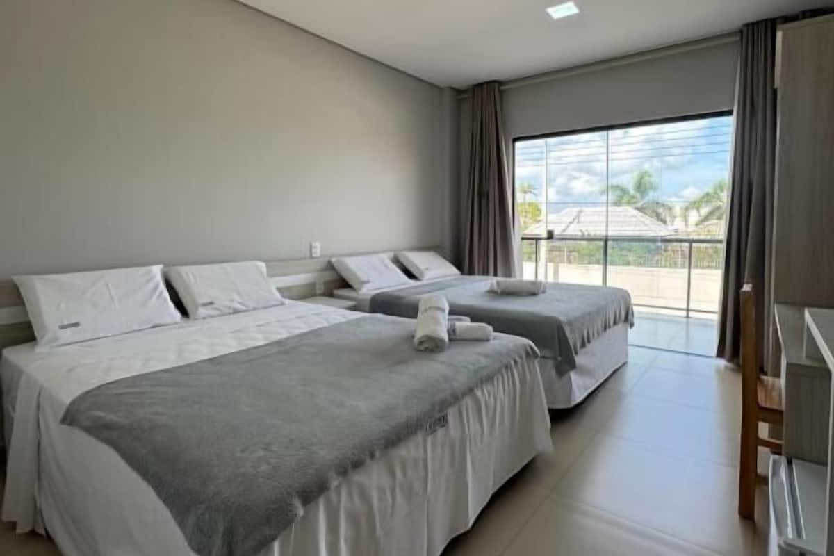 Une chambre d’hôtel avec deux lits, une grande fenêtre et une vue sur l’extérieur.
