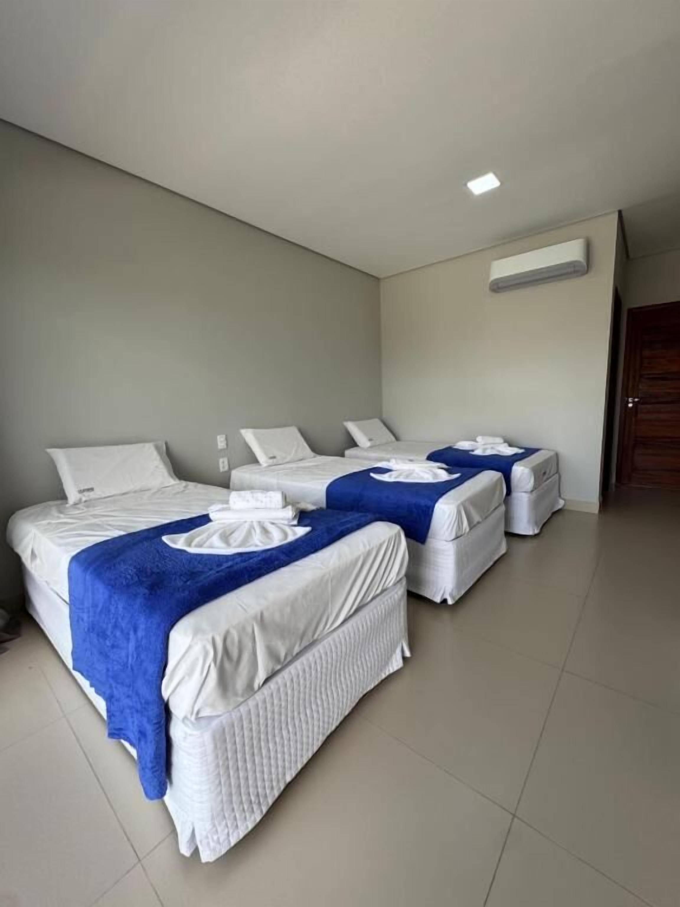 Een hotelkamer met twee bedden, elk voorzien van een blauwe deken en witte kussens.