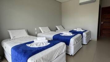 Een hotelkamer met twee bedden, elk voorzien van een blauwe deken en witte kussens.