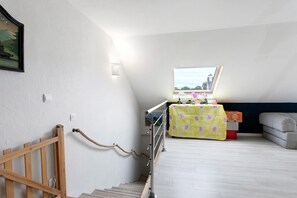 A staircase with a wooden handrail, a metal railing, and a rope handrail. There is a table with a floral tablecloth and a sofa in the background. - Bed and Breakfast 'Chez Lydie' with Shared Terrace, Shared Garden and Wi-Fi (Binic-Étables-sur-Mer)
