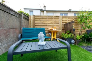 A patio with a table, a blue sofa, and a Buddha statue. - Bed and Breakfast 'Chez Lydie' with Shared Terrace, Shared Garden and Wi-Fi (Binic-Étables-sur-Mer)